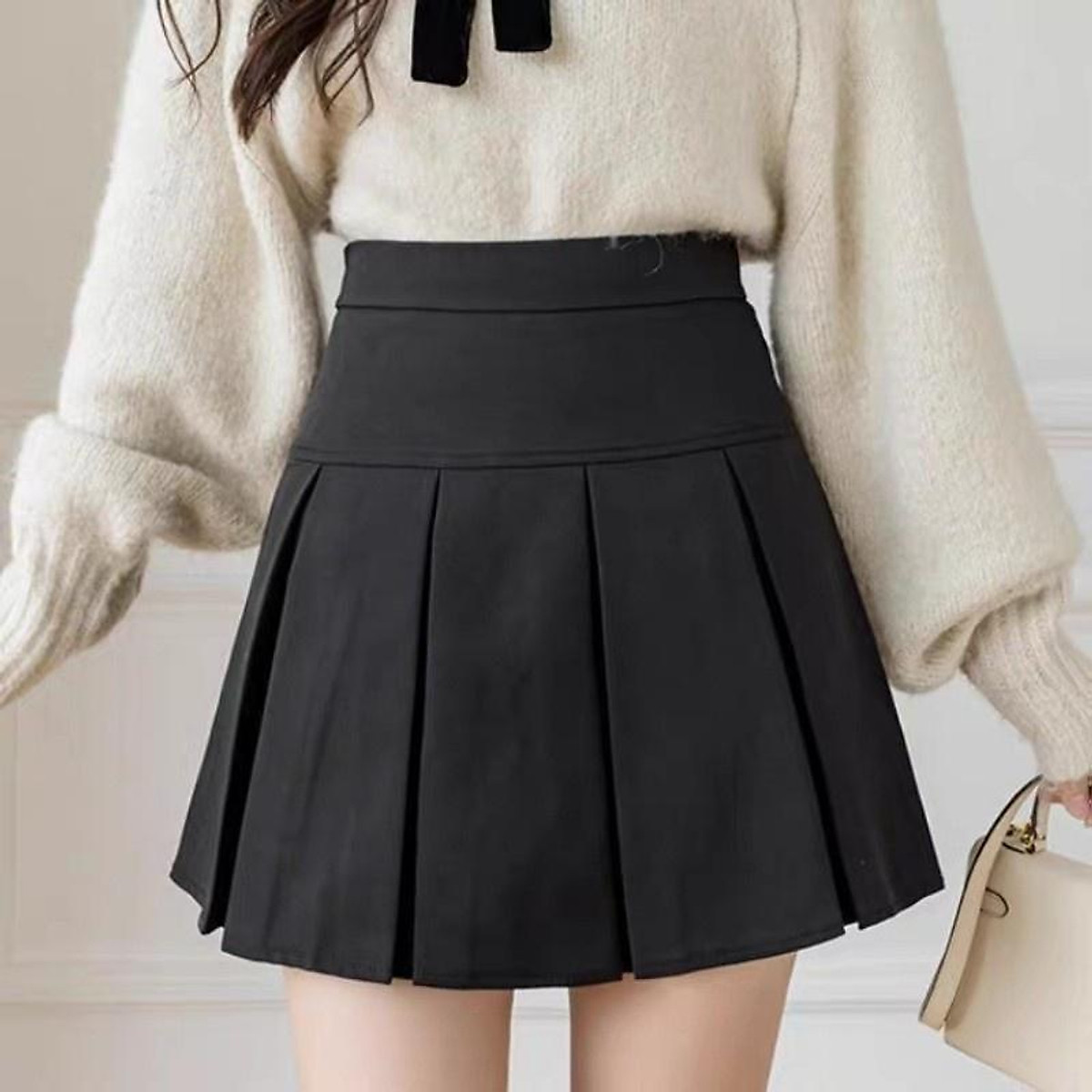 Chân váy xếp ly dáng ngắn đen kết hợp với áo len tay dài theo phong cách Hàn Quốc