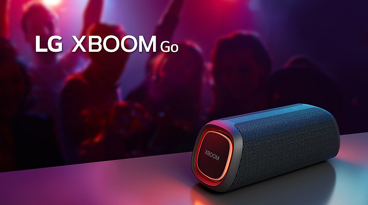 LG XBOOM Go XG5 đặt trên bàn kim loại với đèn màu cam. Sau chiếc bàn, mọi người đang tận hưởng âm nhạc.