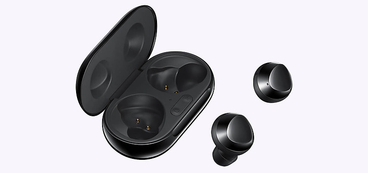 A pair of black earbuds sit parallel to an open charging case.