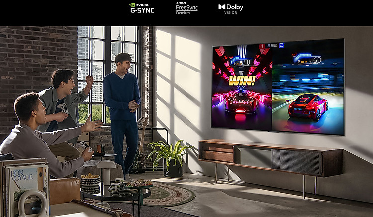 Hình ảnh ba người đàn ông đang chơi một trò chơi đua xe trên TV LG OLED trong một căn hộ hiện đại ở thành phố.