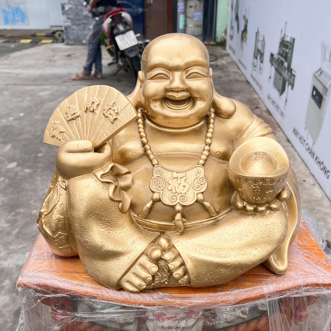 Tượng Di Lặc bột đá màu vàng đồng tay cầm quạt và thỏi vàng cao 25cm