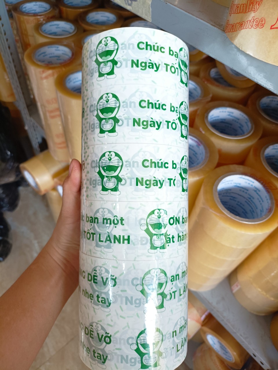 1 cuộn băng keo màu trắng sữa in chữ màu xanh lá, in hình doremon, chữ hàng dễ vỡ