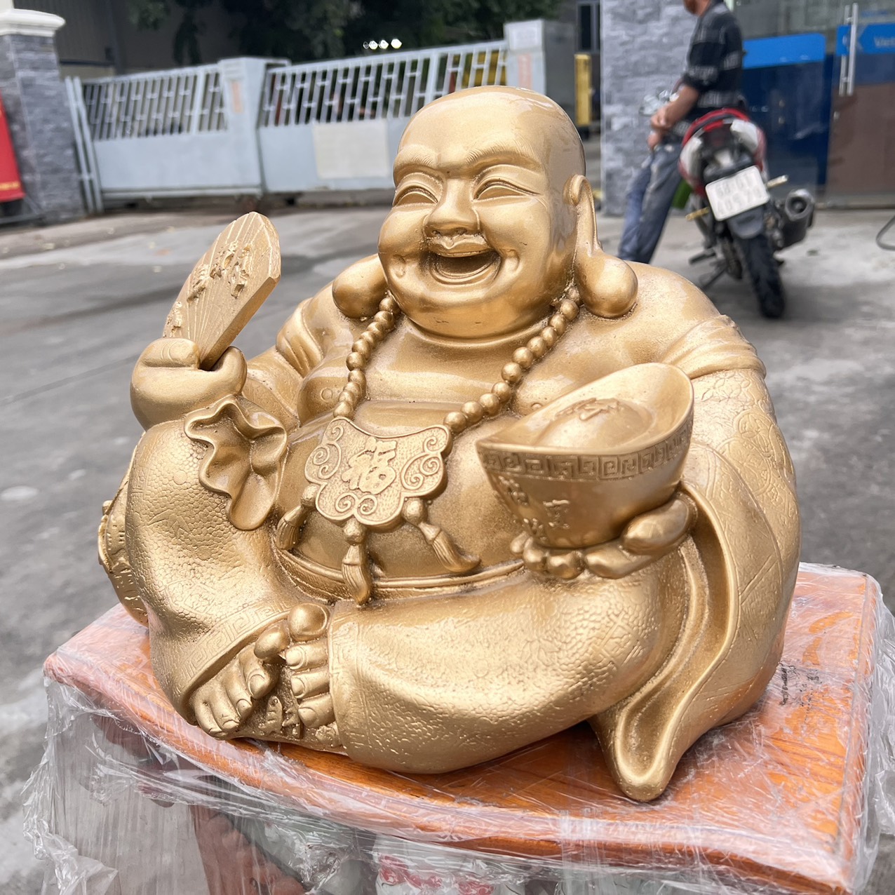 Tượng Di Lặc bột đá màu vàng đồng tay cầm quạt và thỏi vàng cao 25cm