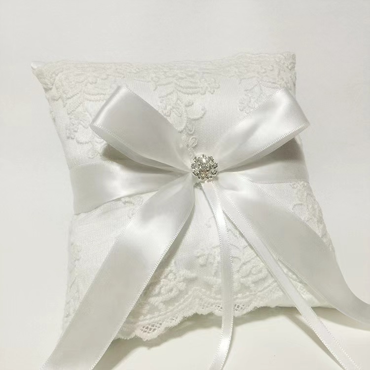 Gối nhẫn cưới mang vòng sa tanh trắng với nơ ruy băng, trang trí pha lê và ren
