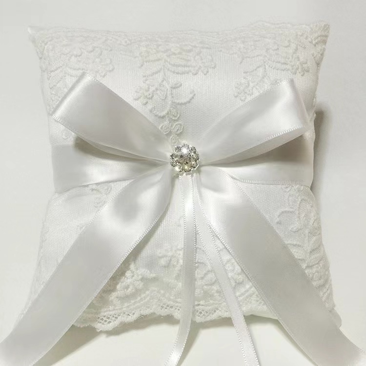 Gối nhẫn cưới mang vòng sa tanh trắng với nơ ruy băng, trang trí pha lê và ren