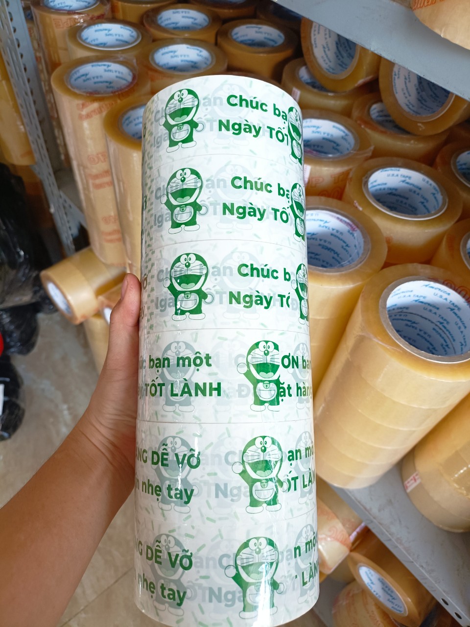 1 cuộn băng keo màu trắng sữa in chữ màu xanh lá, in hình doremon, chữ hàng dễ vỡ