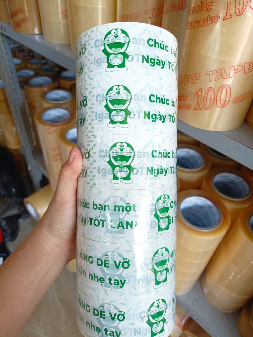 1 cuộn băng keo màu trắng sữa in chữ màu xanh lá, in hình doremon, chữ hàng dễ vỡ