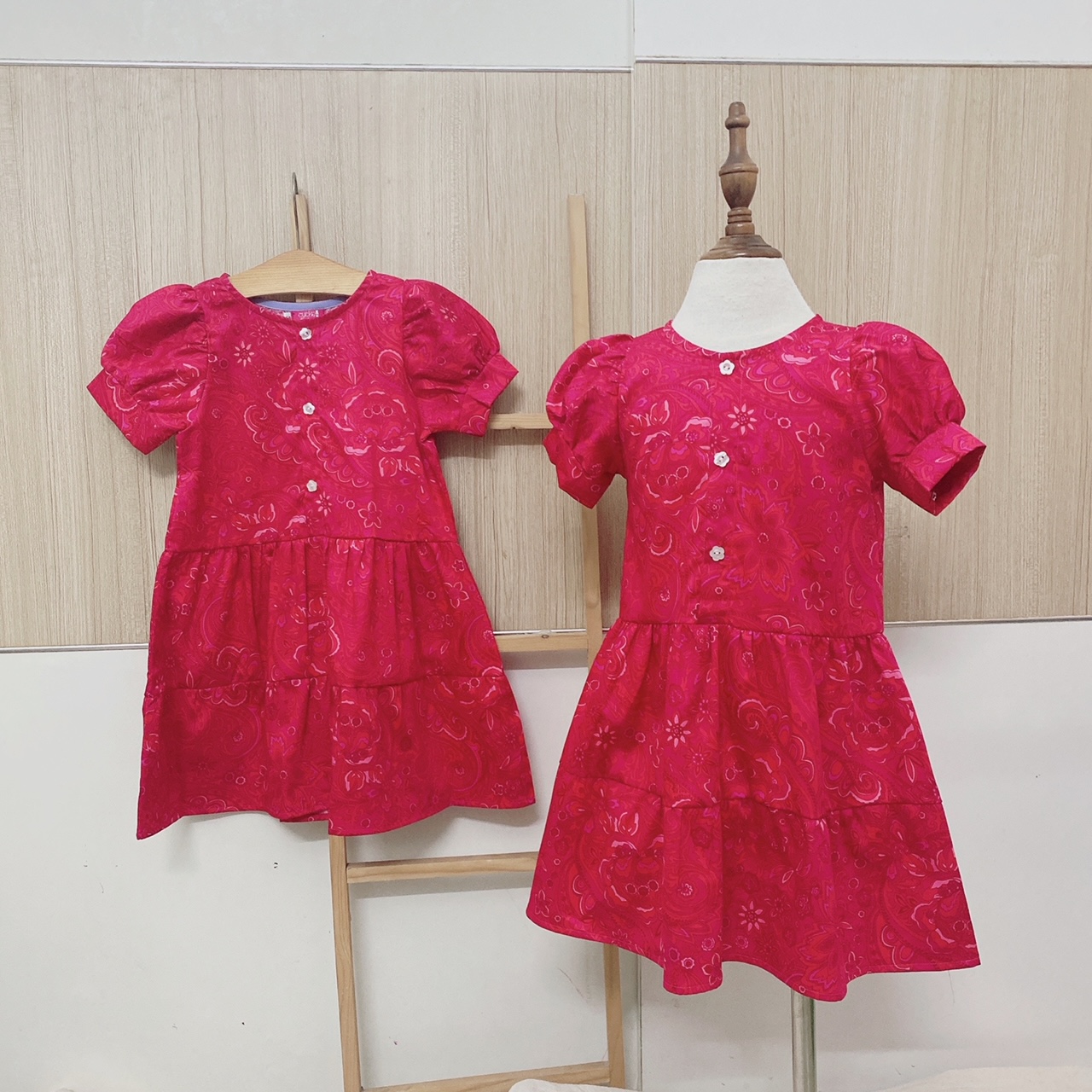 Đầm bé gái đỏ tay hồng gài nút trước