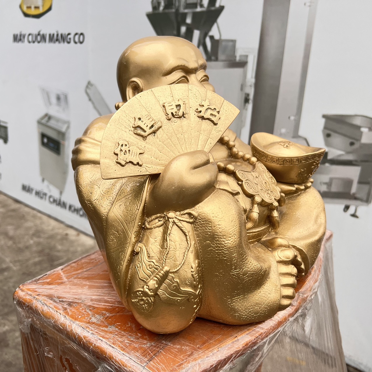 Tượng Di Lặc bột đá màu vàng đồng tay cầm quạt và thỏi vàng cao 25cm