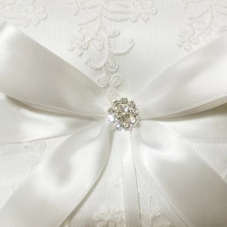 Gối nhẫn cưới mang vòng sa tanh trắng với nơ ruy băng, trang trí pha lê và ren