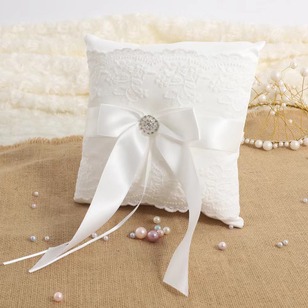 Gối nhẫn cưới mang vòng sa tanh trắng với nơ ruy băng, trang trí pha lê và ren