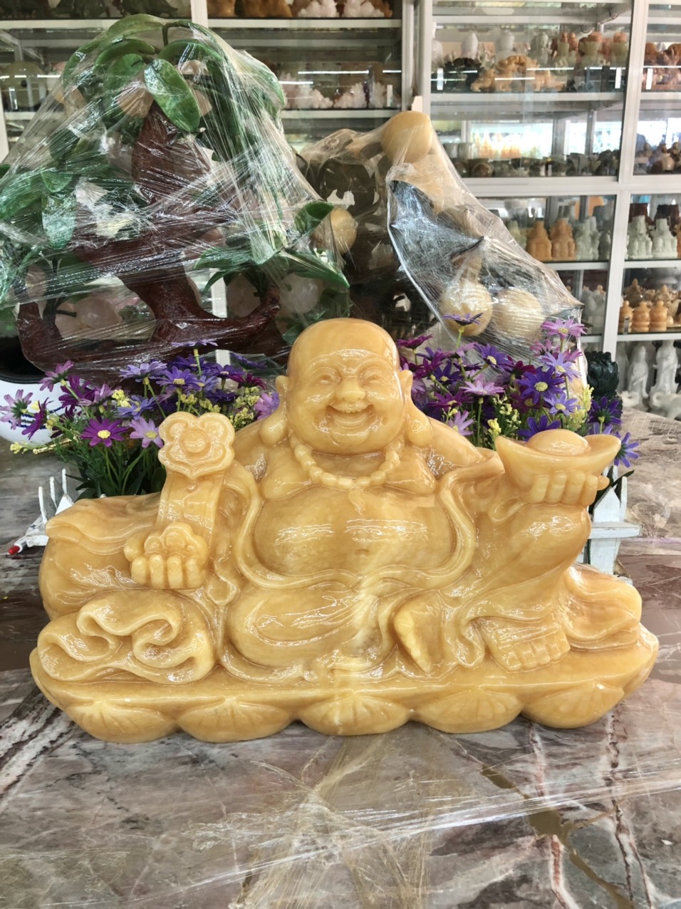 Hình ảnh Tượng Phật Di Lặc ngồi tựa bao tiền cầm thỏi vàng và gậy như ý phong thủy đá ngọc hoàng long - Dài 40 cm