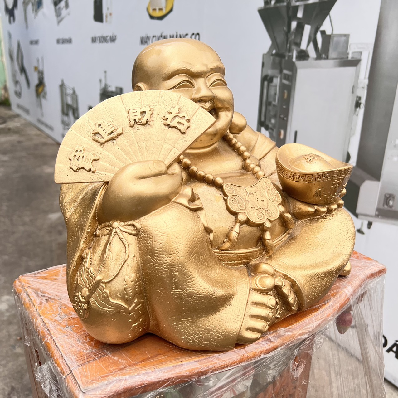 Tượng Di Lặc bột đá màu vàng đồng  tay cầm quạt và thỏi vàng cao 25cm