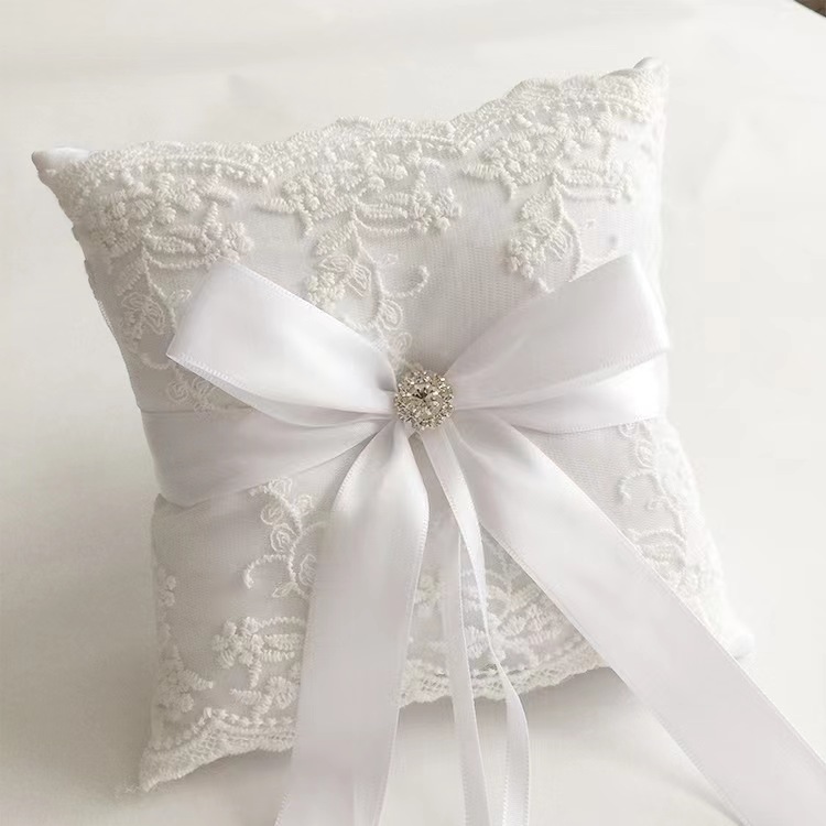 Gối nhẫn cưới mang vòng sa tanh trắng với nơ ruy băng, trang trí pha lê và ren