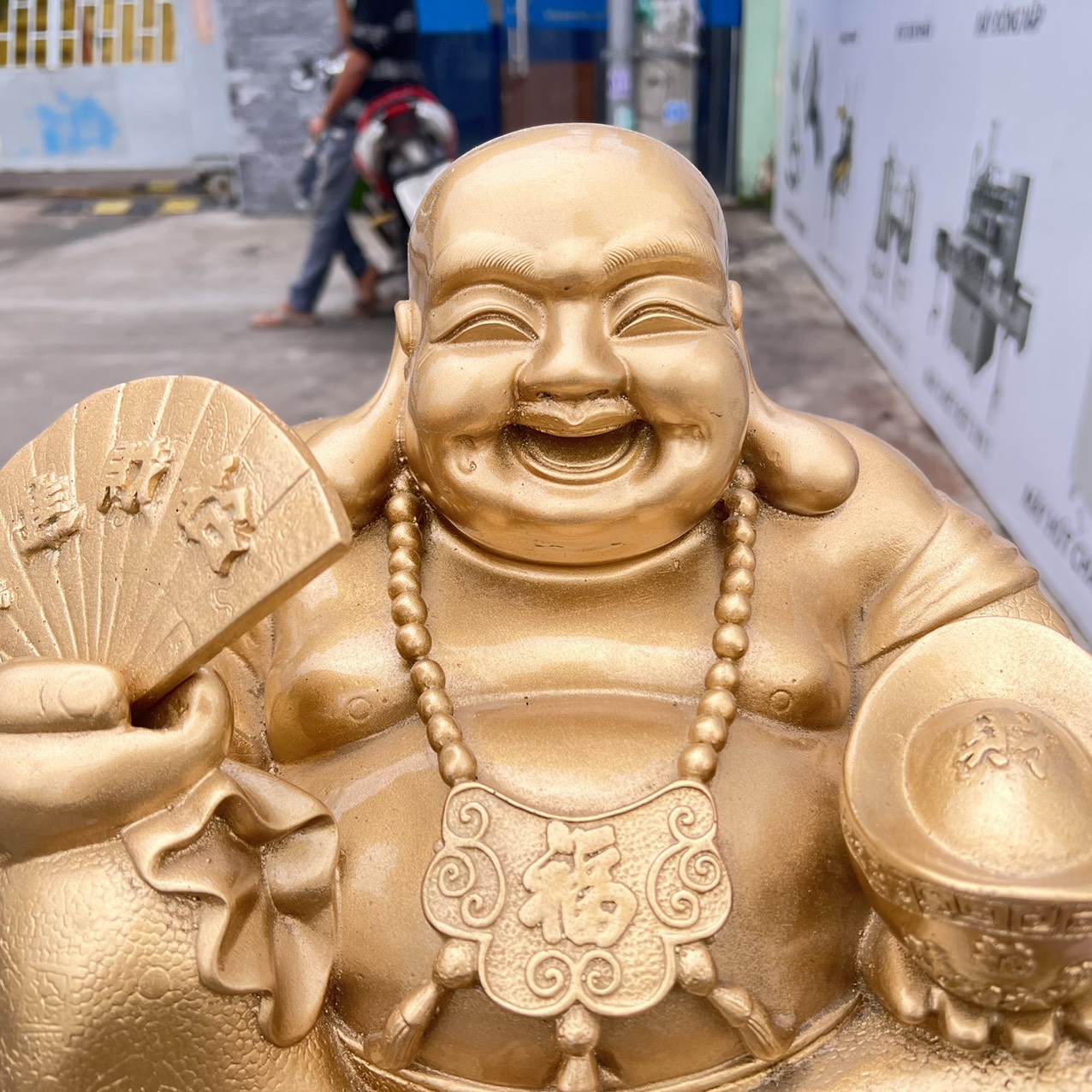 Tượng Di Lặc bột đá màu vàng đồng tay cầm quạt và thỏi vàng cao 25cm