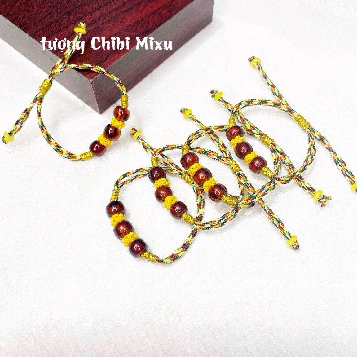 Vòng tay hổ phách màu đỏ nâu tết dây ngũ sắc cho bé