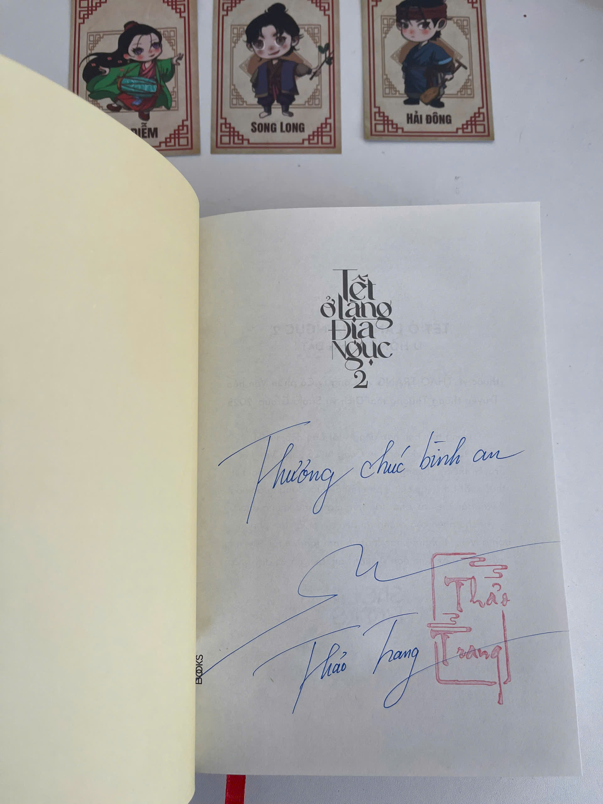 Sách - Tết Ở Làng Địa Ngục Phần 2 - U Hồn Tượng Đất - Saola Books - Thảo Trang - Bìa cứng - chữ ký tác giả - triện tên - bookmark giấy -bookmark mica - 3 thiệp chibi nhỏ - huy hiệu bìa sách