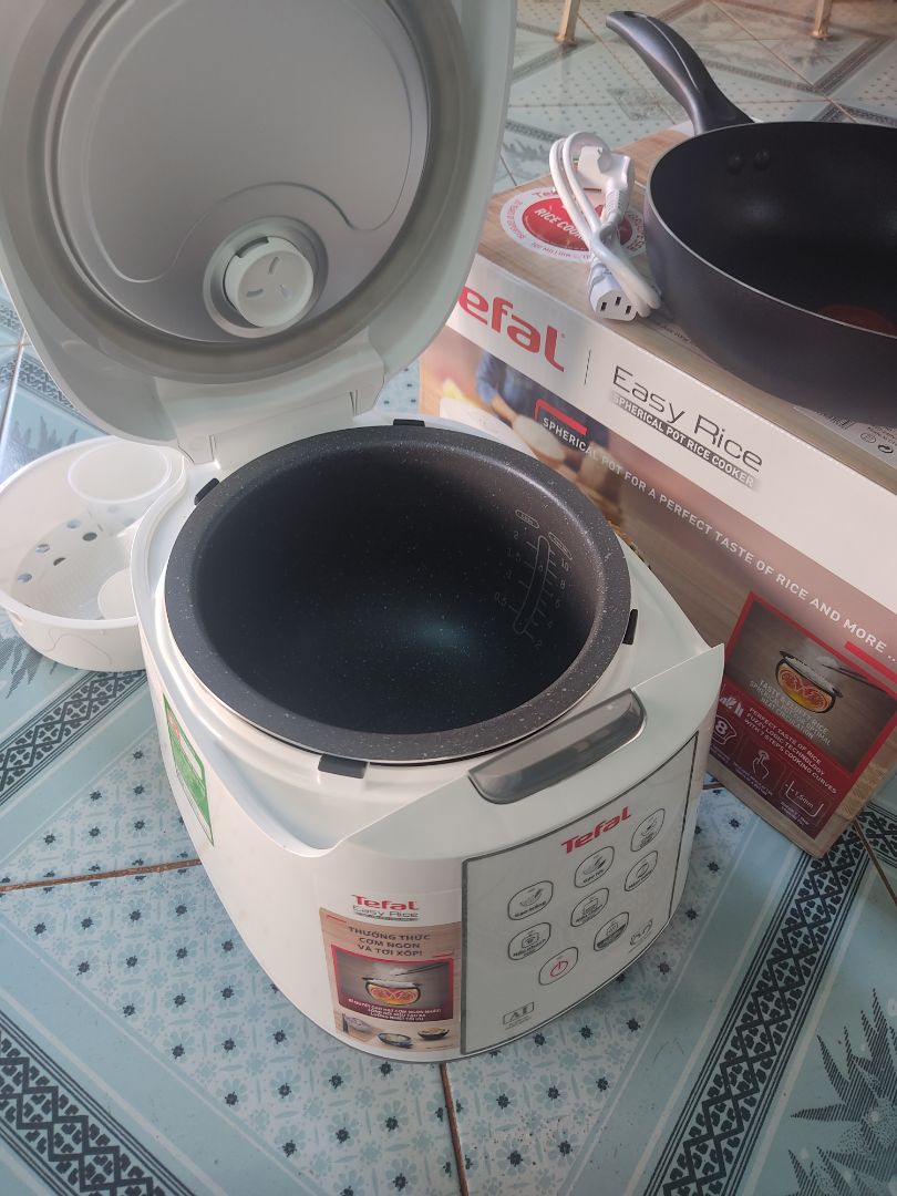 Nói về thương Hiệu Tefal là nói về sự hài lòng và an tâm về chất lượng rồi. Mẹ mình sử dụng rất chi là ưng luôn?. Sau khi sử dụng mình có một số đánh giá như sau:
+ Về thiết kế: Đẹp, sang trọng, màu trắng nhìn rất là đẹp luôn✨✨. Lòng nồi thì hình niêu tráng men nấu cơm không bị dính, không cháy, ngon cơm. Nồi không có tay xách nên một vài bạn đánh giá bất tiện, nhưng mình vẫn thấy nó có cái hay của nó, khi di chuyển nồi ta bưng bê, thay vì xách sẽ an toàn hơn và giúp nồi sử dụng được bền hơn.❤️. Một điểm khác biệt mà nếu để ý kĩ bạn mới biết là thành lòng nồi Tefal in cả logo của mình lên luôn, sang trọng hẳn lên, mình thấy các hãng khác không làm thế (chắc để tiết kiệm chi phí sản xuất). À mà ngoài xửng hấp và môi cơm như bao nồi cơm điện khác, Tefal còn tâm lý  cho khách hàng khi đi kèm thêm 1 môi múc cháo/canh nữa, yêu thế ???
+ Về chức năng: Có rất nhiều chức năng cho một nồi cơm điện với giá quanh 1 triệu đồng như thế này:  Gạo trắng, gạo lức, cháo/canh, nấu nhanh/hấp, nấu chậm/hầm, hâm nóng. Mình thì khoái chế độ gạo lức vì mình rất thích món sữa chua nếp cẩm ??Khi sử dụng chế độ nào thì nút sáng bật ở chế độ đó giúp người sử dụng rất dễ nhận biết. ❤️
+ Về khả năng giữ ấm: Nồi giữ nhiệt rất là lâu, nấu buổi trưa để đến chiều cơm vẫn còn ấm. Có thể là do nồi được thiết kế dạng niêu nêu mới hỗ trợ giữ ấm lâu như vậy.❤️Thêm vào đó ron cao su ở phần nắp rất dày, dẻo đảm bảo hơi được giữ kín như bưng trong nồi nữa
+ Về quà tặng: Theo mình nghĩ với mức giá đã giảm chưa tới 1 triệu là quá ok cho một nồi cơm điện Tefal như thế này rồi, nhưng Tefal lại còn tặng thêm 1 chảo chống dính có tem đỏ báo nhiệt, thành chảo cao giúp hạn chế bị bắn dầu mỡ khi chiên xào thì lại quá là xuất sắc luôn. 
Nói tóm lại là quá nên mua mọi người ạ. Mình đã tin mua và cả nhà mình rất hài lòng về Tefal