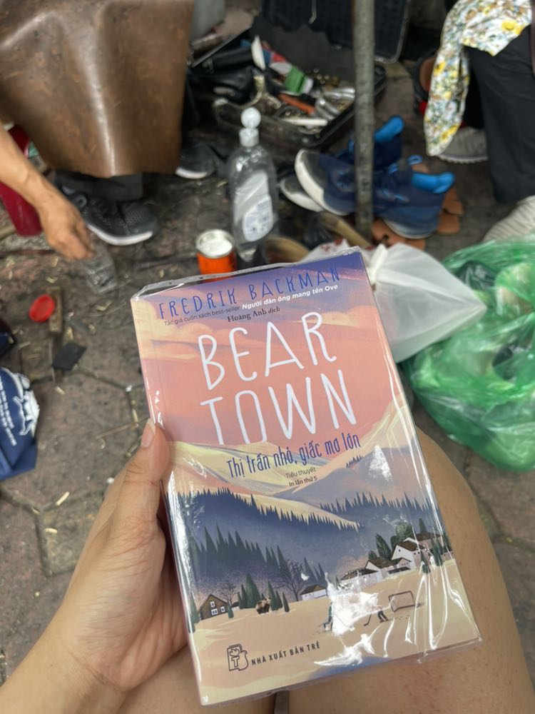 Beartown: Khi thể thao không chỉ là thể thao

Cốt truyện của Beartown thoạt nghe có vẻ đơn giản: một thị trấn nhỏ sống và thở cùng khúc côn cầu. Nhưng đừng để sự giản dị đó đánh *** bạn. Khi một sự cố chấn động xảy ra, nó không chỉ thử thách niềm tin vào những giá trị mà mỗi người gìn giữ, mà còn phơi bày tâm lý con người một cách trần trụi. Cuốn sách khắc họa rõ nét cách mỗi cá nhân chọn phe, cách kẻ mạnh dù sai trái vẫn hiên ngang đứng vững. Đây là một thực tế mà phần lớn chúng ta đều đã từng chứng kiến hoặc nghe nói đến, nhưng Beartown lại từ tốn dẫn dắt người đọc qua từng lớp lang lý do dẫn đến cái kết nghiệt ngã đó.

Điều mình thực sự yêu thích ở cuốn sách này chính là cái kết. Nó không hề quá "dark" hay ám ảnh như nhiều người có thể nghĩ, mà ngược lại, rất tuyệt vời và giàu tính nhân văn. Cái kết cho thấy một cách "trả thù" thấm thía, vừa vặn và sức mạnh thực sự nằm ở đâu. Nó củng cố 1 niềm tin về tính công bằng trên thế giới này: dù kẻ mạnh trông có vẻ như luôn thắng (dưới góc nhìn của số đông), nhưng chỉ có người tử tế thì mới được thanh thản trong lòng. Trong nhiều trường hợp, họ là bên yếu hơn, bị xã hội chỉ trích, chà đạp, nhưng sức mạnh nội tâm và sự buông bỏ quá khứ, hướng đến tương lai chính là điều khiến họ thanh thản và toả sáng. Đó là sức mạnh thực sự, là thứ mà kẻ sai nhưng (được coi là) mạnh không bao giờ có được.

Lối viết của Fredrik Backman chính là tinh hoa làm nên sức hấp dẫn của Beartown. Dù bạn chưa từng biết gì về khúc côn cầu, Backman vẫn khiến bạn tò mò, hiểu hơn về môn thể thao này, và đặc biệt – ông biến bạn thành một người dân thực thụ của thị trấn Bear Town. Đọc sách mà cứ ngỡ như mình đang đi dạo quanh thị trấn, hiểu rõ từng gương mặt trong danh sách dài dằng dặc các nhân vật: từ Benji, Amat, Kevin, Ana, Maya, Leo, cho đến ông Sune, chú David, chú Peter, cô Mira... Mình thực sự rất háo hức để tiếp tục đọc cuốn thứ hai!