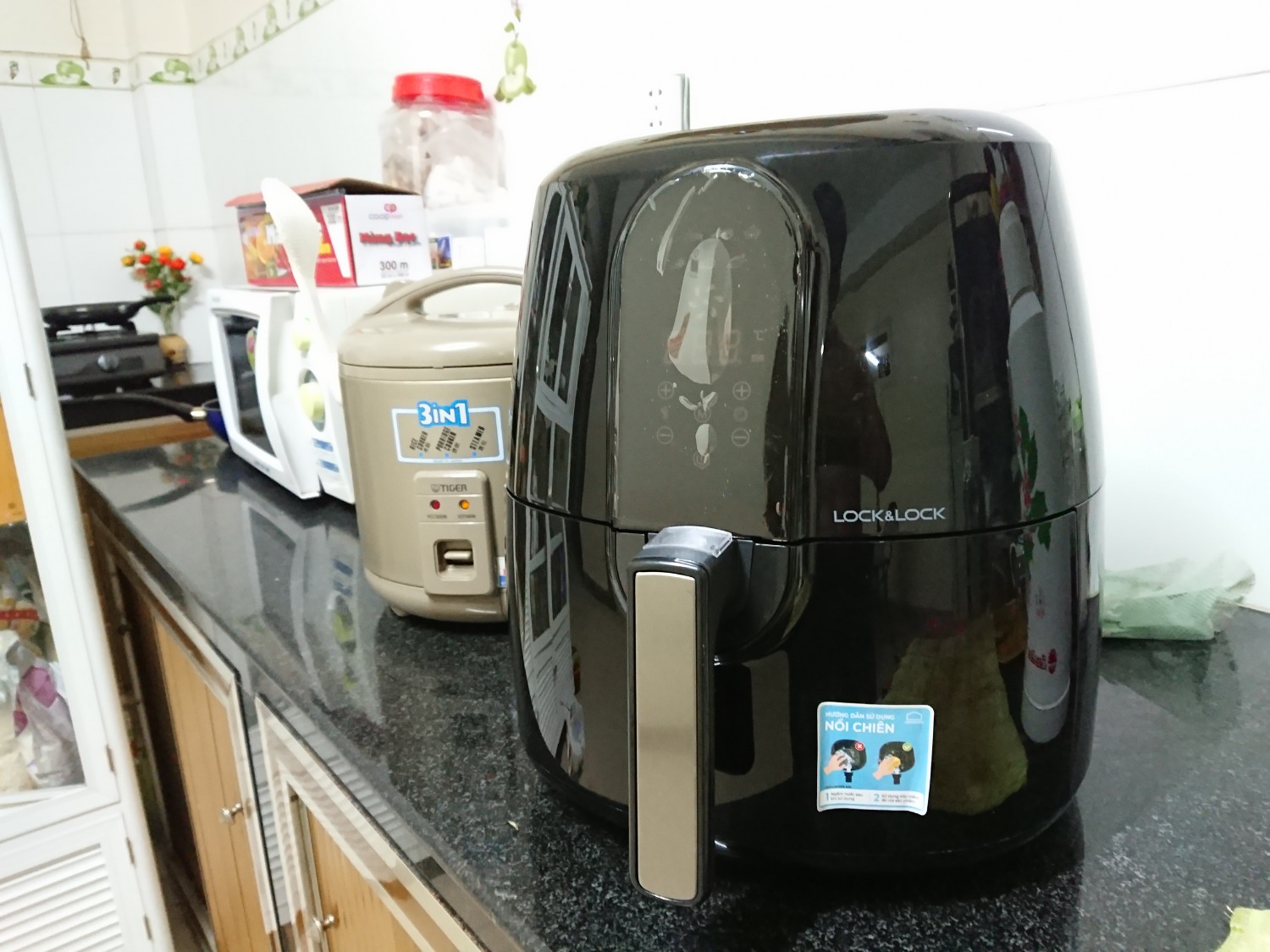 Một sản phẩm cồng kềnh và lần nay Tiki đóng gói cẩn thận hơn khi có thêm hộp giấy bọc lại hộp Lock&Lock (lần trước tôi mua máy pha cà phê chỉ có bọc nylon, hộp bị móp méo tại cảm giác hàng không mới).
Bỏ qua vấn đề giao nhận hàng, nguyên lý hoạt động của nồi chiên không dầu tương tự lò nướng gồm thanh nhiệt và luồng khí nóng luân chuyển quanh thức ăn. Với chất lượng Lock&Lock, nguyên lý này sẽ hoạt động gần như hoàn hảo. Thực phẩm chín đều, giữ nguyên mùi vị của thực phẩm. Đặc biệt cảm nhận vị khoai tây chính cống ở món khoai tây chiên (khi mà trước đây tôi ăn chỉ toàn là mùi dầu ăn). Tuy nhiên với những món thái nhỏ, hoặc như chả cá viên sẽ khó chín đều (ở khoảng 75%). 
Dưới khay để đồ ăn khắc các lỗ tròn để nước giọt xuống. Phần này tôi thích hãng làm các đường chéo đan nhau hơn vì khi làm beefsteak, phần dưới miếng bò in lỗ như bị giác hơi.
Chức năng của máy chỉnh qua nút cảm ứng rất nhạy, màn hình hiển thị con số to rõ. Thao tác kéo/đẩy học thức ăn khá mượt nhưng phải canh đúng đường trượt khay.
p/s: Bạn nên đọc Recipe book kèm theo để biết cách canh thời gian chiên, ướp gia vị,....
Cách tôi hay chiên khoai tây ăn đó là để 165 độ trong 10' để các cọng khoai chín đều rồi tăng lên 195 độ trong vài phút để khoai được giòn, thơm ngon (tùy vào lượng khoai tây mà thời gian chiên sẽ dao động)
Sơ sơ là vậy, các bạn có thể xem thêm review chi tiết tại: https://hiiyall.wordpress.com/