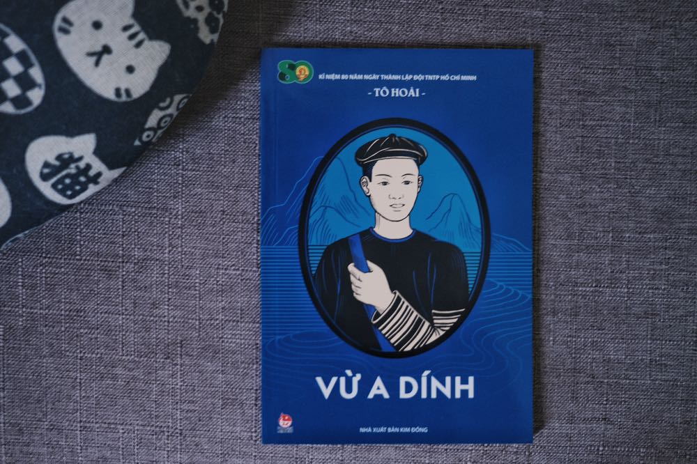 Vừ A Dính là một tác phẩm nằm trong Bộ ấn phẩm kỉ niệm 80 năm ngày thành lập Đội TNTP Hồ Chí Minh (15.5.1941 – 15.5.2021). Tác phẩm là một truyện kí, được viết lại bởi nhà văn Tô Hoài. 
Sách có khổ nhỏ, chỉ dày 66 trang (tức là rất mỏng). Số lượng chữ cũng không nhiều, do mỗi chương đều có hình minh hoạ rất đẹp. Nhìn chung đây là một tác phẩm phù hợp dành cho thiếu nhi.

Tóm tắt: Cuốn sách kể về Vừ A Dính, một thiếu niên dân tộc Mèo tham gia vào cuộc kháng chiến chống Pháp ở Lai Châu và đã anh dũng hi sinh khi mới 15 tuổi. A Dính làm nhiệm vụ canh gác, liên lạc, tiếp tế cho lực lượng kháng chiến bị thực dân Pháp bao vây. Nhiều lần đụng độ với địch, A Dính đều thể hiện sự gan lì, thông minh, nhanh trí của mình. Cho đến khi cậu lọt vào ổ phục kích của giặc...

Điểm đặc biệt của cuốn sách kí này là nó mô tả cuộc đời của Vừ A Dính thông qua nhiều người dẫn chuyện khác nhau. Từ việc bà con làng xóm ai cũng biết đến cậu, đến người anh ruột, hay là người lính nguỵ tham gia vào việc bắt bớ A Dính. Truyện đọc khá cảm động, chỉ tiếc là vì cách kể chuyện đặc biệt này khiến cho mạch truyện hơi rời rạc. 

Đánh giá cá nhân: 3/5


Tác phẩm khá ngắn, chỉ bao gồm 66 trang khổ nhỏ. Truyện được Tô Hoài kể lại thông qua nhiều người dẫn chuyện khác nhau, là những bà con làng xóm, người anh ruột, hay là người lính nguỵ tham gia vào việc bắt bớ A Dính. Truyện đọc cảm động, tuy nhiên không toát được lên chất văn của Tô Hoài.