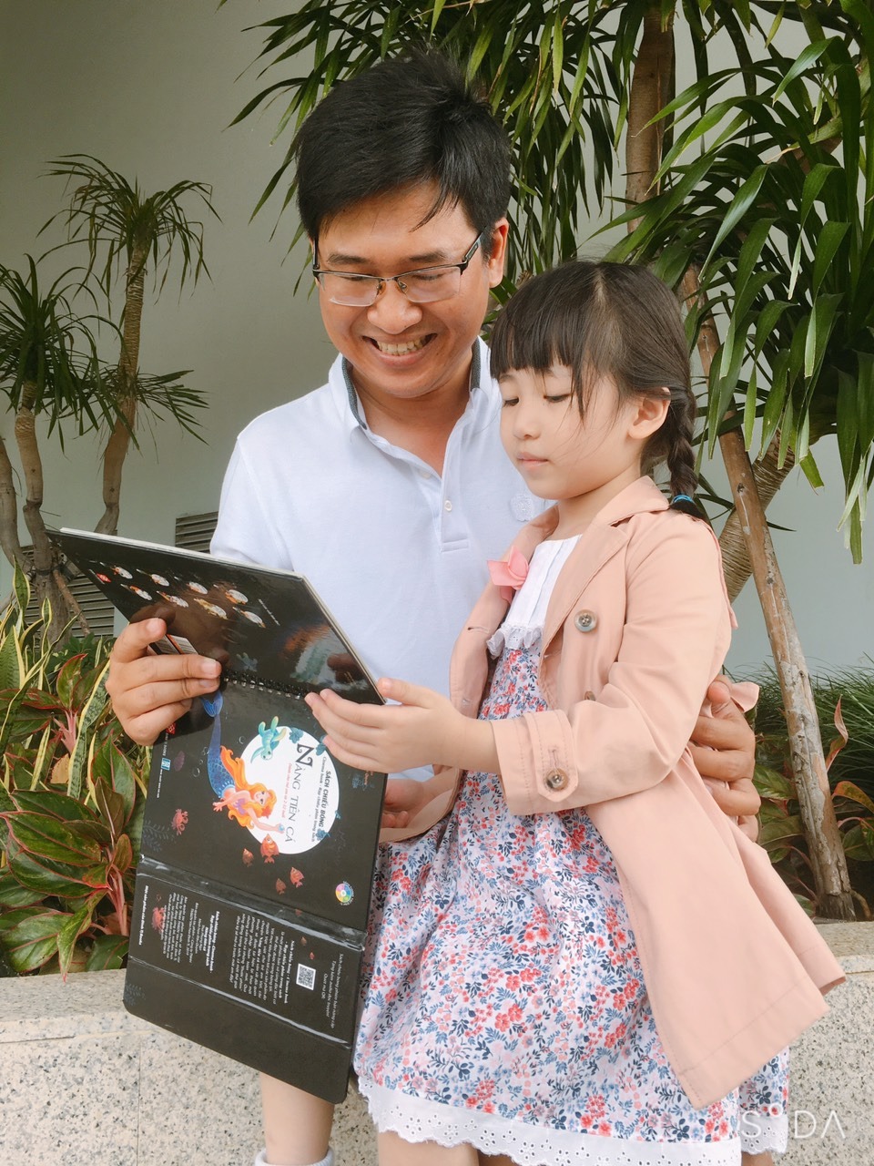 Hồi tôi còn nhỏ có lần má dẫn tôi đi coi chiếu bóng ngoài ủy ban xã, từ chiều má đã giục tôi ăn cơm tắm rửa để tối cả nhà kéo nhau ra đó, xem chiếu bóng thời ấy như một ngày hội thật sự người già trẻ con, nam thanh nữ tú hồi hộp theo từng cảnh chiếu phim lưu động. Những ngày tháng bé thơ ấy thực sự là những kỷ niệm tuyệt vời đong đầy trong ký ức tôi đến mãi sau này, tôi chẳng thể nào quên được cảm giác tò mò ngơ ngác của những đứa trẻ nơi làng quê nghèo xơ xác, trẻ con giữa thời đại mà mọi thứ phát triển vũ bão như bây giờ thật chẳng thiếu bất cứ điều gì. Nhưng cái gì cũng có mặt lợi và mặt hại, tôi không cấm con tiếp cận với điện thoại hay internet nhưng tôi biết cái gì nên hạn chế, tôi không muốn nhìn con gái bé xíu mắt đã đeo đôi kính cận dày cộp hay cứ mải mê với youtube xem phim hoạt hình. Tôi muốn giữ cho tuổi thơ con trong trẻo và hồn nhiên, tôi muốn nhìn con lớn lên theo cách tự nhiên như tôi ngày xưa. Hàng tuần niềm vui của hai cha con là được đi nhà sách, dù con còn bé tôi vẫn muốn bé tiếp cận với những quyển sách đầy ý nghĩa, được đọc sách cho con nghe là thói quen mỗi ngày, là niềm vui bé nhỏ sau một ngày dài bôn ba ngoài xã hội tôi muốn mình góp mặt trong hành trình khôn lớn cùng con. Hôm rồi vô tình trông thấy những quyển sách cinema book này trên Tiki được giảm giá rất mới mẻ nên đã mua thử về cho con gái xem, khi chiếu cho con gái xem quả thực tôi vô cùng xúc động cảm giác như kỷ niệm của 30 năm trước chợt ùa về, tôi thấy tuổi thơ mình đang trở lại trong hình hài bé nhỏ của con. Con gái hào hứng và háo hức theo dõi những trang sách chiếu trên tường kèm giọng đọc kể chuyện thật du dương, quyển sách như chiếc chìa khóa kì diệu mở ra những cánh cổng đưa con đến vùng đất thần tiên, nó khơi dậy những giác quan tiềm ẩn trong con. Con gái thỏa thích đắm chìm trong những câu chuyện cổ tích quen thuộc với bao thế hệ, được tiếp cận văn học đọc theo cách mới mẻ và độc đáo, bé ghi nhớ lâu hơn những tình tiết trong sách, những hình vẽ tỉ mỉ trong từng trang sách hiện lên thật đẹp đẽ thu hút cả với tôi – người đàn ông đã qua tuổi nhi đồng từ lâu lắc. Với tôi sách luôn là suối nguồn tri thức bất tận của tâm hồn, dù thế giới có thay đổi đến đâu tôi vẫn giữ nguyên sở thích đọc và thói quen lần giở từng trang sách như xưa, cảm giác lắng đọng lòng mình theo từng con chữ thật thú vị và giúp tâm hồn thêm tĩnh lặng. Tôi thấy hạnh phúc khi nhận ra con gái cũng bắt đầu yêu thích sách, dù con vẫn chưa biết đọc nhưng cảm giác háo hức khi được ba mẹ mua tặng những quyển sách vẫn làm tôi thấy vui, trẻ con là mầm xanh nhỏ xíu tính cách được nuôi dưỡng chăm chút kỹ từ nhỏ sau này chắc chắn sẽ thành một cây xanh tươi tốt. Tôi chọn cho con thật nhiều sách có ảnh minh họa sinh động cho bé dễ tiếp thu, những quyển sách như rạp chiếu bóng trong nhà bổ trợ rất nhiều cho tôi khi muốn truyền cảm hứng yêu sách cho con. Tuổi thơ con rồi sẽ đi qua không bao giờ trở lại tôi muốn cùng con gìn giữ nó thật nâng niu bởi tôi biết thời gian như chuyến tàu tốc hành một đi không trở lại, tôi muốn mình bên con trong suốt những năm tháng tuyệt vời này, tôi muốn dệt nhiều yêu thương cho tuổi thơ con mãi đẹp. Và những quyển sách đã được kiểm duyệt kỹ càng với nội dung chọn lọc của Tiki sẽ là người bạn đồng hành đáng tin cậy cùng tôi nâng cánh ước mơ con từ nay và mãi mãi về sau.