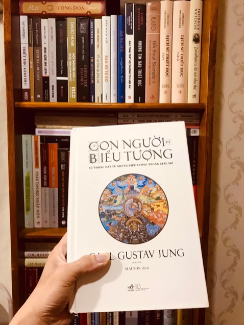 Trước khi review quyển này cần nói một tí về người review ạ.
Tôi không được đào tạo chuyên môn về Tâm lý học nên Phân tâm học hay Tâm phân học (xin phép gọi chung là Phân tâm học từ sau đoạn này) càng không phải. Tôi chỉ là một người tò mò thích tìm hiểu nên từng mê mẩn với các lý thuyết của Freud và đọc qua một ít sách và bài giới thiệu về Jung. Nhưng với tôi, quyển sách này (Con người và biểu tượng) không khó hiểu - điều này có lẽ là nằm trong mục đích của Jung và các đệ tử, đồng nghiệp của ông khi biên soạn quyển sách này là dành cho đại chúng. Nói vậy để những bạn đọc có quan ngại quyển này khó hiểu cũng an tâm phần nào rồi ạ.
Cấu trúc của quyển sách chia thành các chương với mỗi chương là một chủ đề độc lập (do mỗi tác giả khác nhau viết) nhưng có một sợi dây liên kết nhất định. 
Những điều đọng lại sau khi tôi đã đọc xong quyển này.
1. Tôi đã từng yêu thích lý thuyết Phân tâm học nhưng đã từ bỏ sau một thời gian do cảm thấy nó sa vào tư biện và sai lầm ở vấn đề chọn mẫu (mẫu là những người thực sự có vấn đề tâm lý nhưng Freud kết luận cho tâm thần nhân loại). Hơn nữa qua đọc quyển Lịch sử thượng đế (Karen Armstrong), tôi đồng tình với bà rằng Phân tâm học là một dạng thần bí của khoa học. Nhưng qua Con người và biểu tượng, tôi rút ra 2 việc quan trọng (1) Jung không cho rằng các biểu tượng (cổ mẫu) xuất hiện trong các giấc mơ của tất cả mọi người là có thể lý giải như nhau mà phải tuỳ thuộc vào từng trường hợp cụ thể; (2) các hiện tượng thần bí không phải phương pháp của Phân tâm học mà là phương tiện để đi vào vô thức. Cụ thể Jung cho rằng việc bói bài Tarot hay giải mã các giấc mơ đều có giá trị như nhau trong việc cố gắng đi vào vô thức của người đang được phân tích tâm lý. Ở chương gần cuối, kinh Dịch cũng được sử dụng với phương thức tương tự.
2. Ở chương đầu, Jung cũng nói khá cụ thể sự khác nhau giữa lý thuyết của ông và người thầy, người đồng nghiệp của mình - Freud. Chương tiếp theo giới thiệu một số cổ mẫu trong lý thuyết của Jung nhưng khá sơ lược vì vậy tôi cho rằng nên đọc thêm các bài phân tích khác (ngoài sách) để bổ trợ việc hiểu các cổ mẫu này.
3. Tôi không hiểu nghệ thuật trừu tượng và từng đọc qua quyển Câu chuyện nghệ thuật (E. H Gombrich) với hy vọng ít nhất hiểu được các nghệ sĩ ấy đang làm gì, câu trả lời của Gombrich là nghệ thuật để giải quyết những vấn đề được đặt ra trong từng giai đoạn của nghệ thuật và từng nghệ sĩ cũng tự đặt ra nhiệm vụ mà tự họ tìm cách giải quyết. Còn câu trả lời của Con người và biểu tượng là một số thể loại trừu tượng là sự tái hiện hình ảnh trồi lên từ vô thức.
4. Quyển sách này đến với tôi khi trước đó ít hôm tôi vừa trải qua một giấc mơ mà bản thân tôi nhận ra mình đã gặp gỡ Ẩn nữ và Cái bóng của mình. Điều đó càng làm tôi có niềm tin hơn vào lý thuyết của Jung và như tìm được sự đồng điệu khi đọc những chương đầu. Thật ra trước khi đọc quyển sách này tôi chỉ nhận diện được Ẩn nữ, các chương đầu đã gợi tôi nhớ về Cái bóng trong giấc mơ đó.
Tóm lại, đây không phải quyển sách quá khó đọc và là một quyển sách tốt dẫn vào lý thuyết Tâm phân học của Jung, nó cũng rất ích lợi cho những người quan tâm các biểu tượng văn hoá. Quyển sách cũng gợi lên một điều mà tôi phải tiếp tục suy nghĩ. Trước giờ tôi vẫn tin rằng việc thờ đá liên quan đến sinh thực khí nam nhưng cách lý giải trong sách này lại khác. Đây là vấn đề mà tôi nghĩ mình cần suy nghĩ thêm và tạm thời chưa có kết luận.
Anh Thụy
Ba Xuyên, 16/02/2023