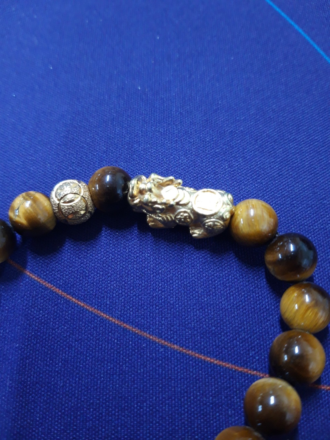 Hạt vòng bên ngoài nhìn đẹp hơn hình mình chụp một chút. Vòng cũng khá nặng tay. Phần tỳ hưu và viên tròn mạ vàng có hơi mỹ kí một tí, thấy chỗ tiếp xúc với hạt vòng bay sạch lớp mạ luôn. Có lẽ do xiết dây chặt quá nên ma sát nhiều làm bong lớp mạ.