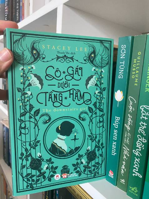 Cô Gái Dưới Tầng Hầm là cuốn tiểu thuyết lịch sử vô cùng hấp dẫn cho chúng ta góc nhìn về cuộc sống của những con người bị đối xử bất công bởi chủng tộc và màu da, trong đó có những người nhập cư Trung Quốc, vào thời kỳ hậu Tái thiết.
Jo Kuan mười bảy tuổi, cho dù khéo léo và tài năng, nhưng luôn buộc mình phải sống như vô hình để tránh xa rắc rối. Cô cùng cha nuôi ở trong căn hầm bí mật nằm dưới một toà soạn báo, và an phận với công việc làm mũ cho các quý bà quý cô yêu thời trang. Nhưng khi bị mất việc và làm hầu gái cho một quý cô của gia đình giàu có bậc nhất Atlanta, Jo đã chứng kiến rất nhiều sự bất công diễn ra trong thành phố của mình. Thất vọng, cô bắt đầu trở thành tác giả ẩn danh cho chuyên mục tư vấn báo chí có tên “Quý cô Ngọt ngào”. Khi chuyên mục của cô trở nên nổi tiếng với những quan điểm cấp tiến về mọi lĩnh vực, đặc biệt là về những bất công trong xã hội, cũng là lúc danh tính của cô bị săn lùng ráo riết khiến cô phải quyết định xem liệu một con người vốn quen ẩn mình trong bóng tối như cô có sẵn sàng bước ra ánh sáng hay không.
Ngoài những dấu ấn lịch sử có thực của thời kỳ này, chúng ta cũng được chứng kiến một bức tranh chân thực về những người phụ nữ da màu bị xã hội cô lập phải đấu tranh trong hai trận chiến - vì bình đẳng giới và bình đẳng chủng tộc.
