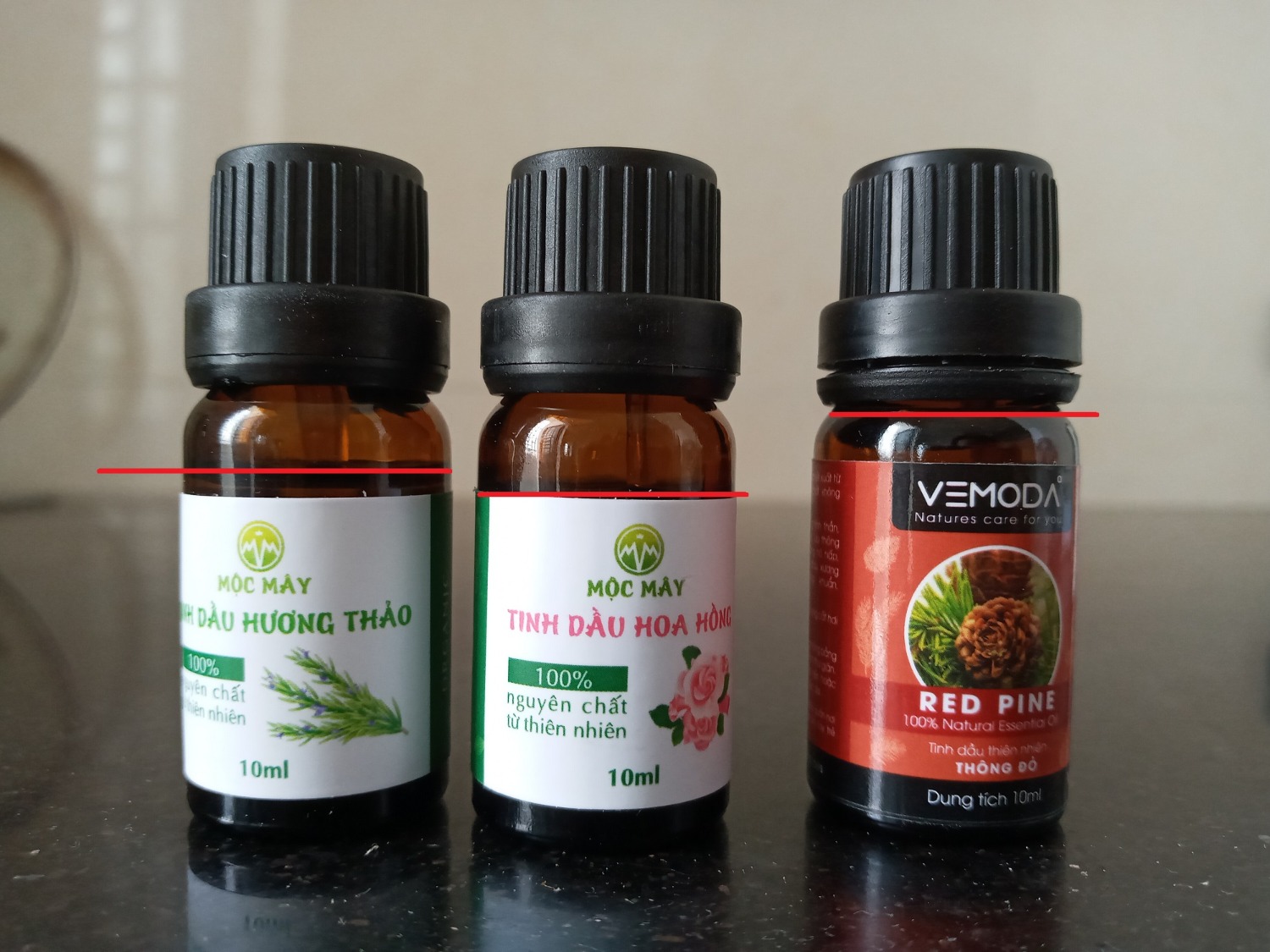 Thứ nhất là không có ngày sản xuất, chỉ ghi HSD là 5 năm.
Thứ hai là lương tinh dầu ít hơn so với các hãng khác, mình đã sử dụng qua các SP của Jullyhouse, Kobi và Vemoda, tinh dầu của 3 hãng nãy đều gần đầy lọ (lọ của các hãng đều giống hệt nhau, trừ dán nhãn), riêng các lọ của Mộc Mây thì số lương ít hơn 10-20%. Suy ra SP trên thực tế chỉ có 8-9ml thôi. Mình đã chụp ảnh lại và đánh dấu vạch đỏ tương ứng với mức tinh dầu chứa bên trong (bên phải là lọ của Vemoda).