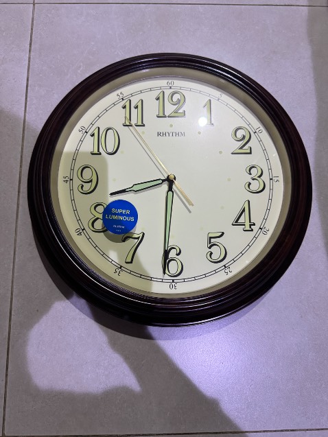 Đồng hồ treo tường thương hiệu Rhythm với thiết kế cổ điển.

	1.	Mặt số rõ ràng, dễ nhìn: Các con số được in lớn, giúp dễ dàng quan sát từ xa.
	2.	Dạ quang trên số và kim: Đồng hồ có chức năng phát sáng trong bóng tối, giúp người dùng nhìn giờ dễ dàng vào ban đêm.