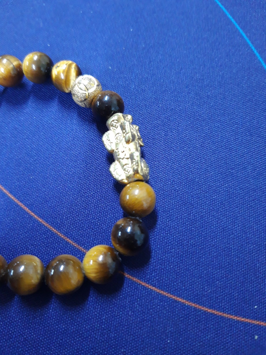 Hạt vòng bên ngoài nhìn đẹp hơn hình mình chụp một chút. Vòng cũng khá nặng tay. Phần tỳ hưu và viên tròn mạ vàng có hơi mỹ kí một tí, thấy chỗ tiếp xúc với hạt vòng bay sạch lớp mạ luôn. Có lẽ do xiết dây chặt quá nên ma sát nhiều làm bong lớp mạ.